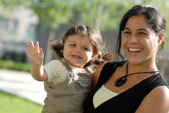 A mother carrying her baby girl smile on a sunny day. 