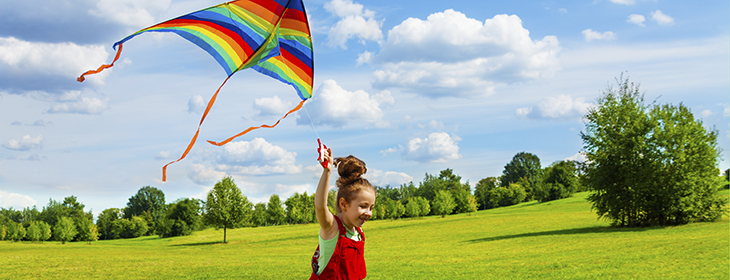 Cute little girl with long hair running with kite in the field on summer sunny day