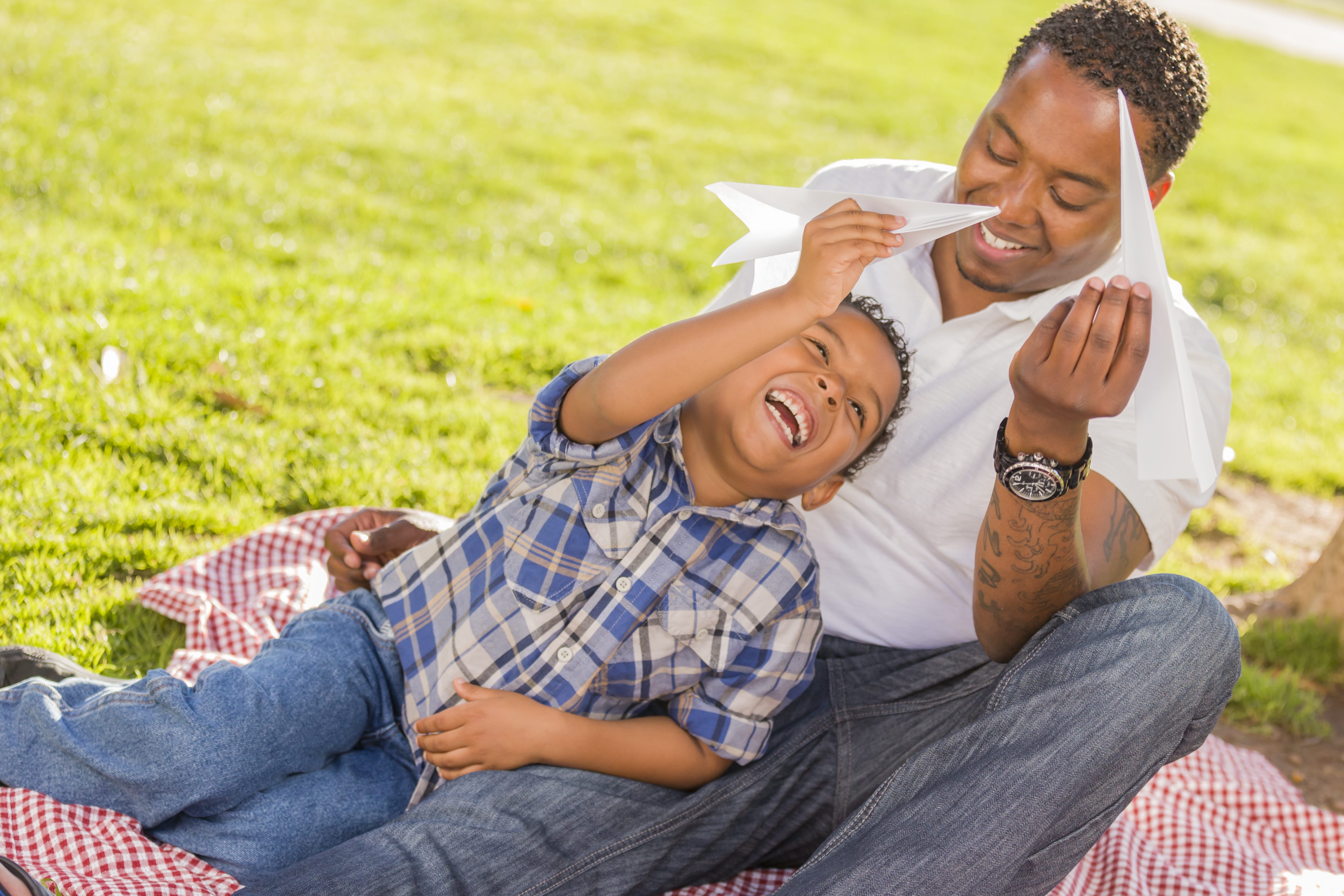 Mixed race father and son playing with paper airplanes