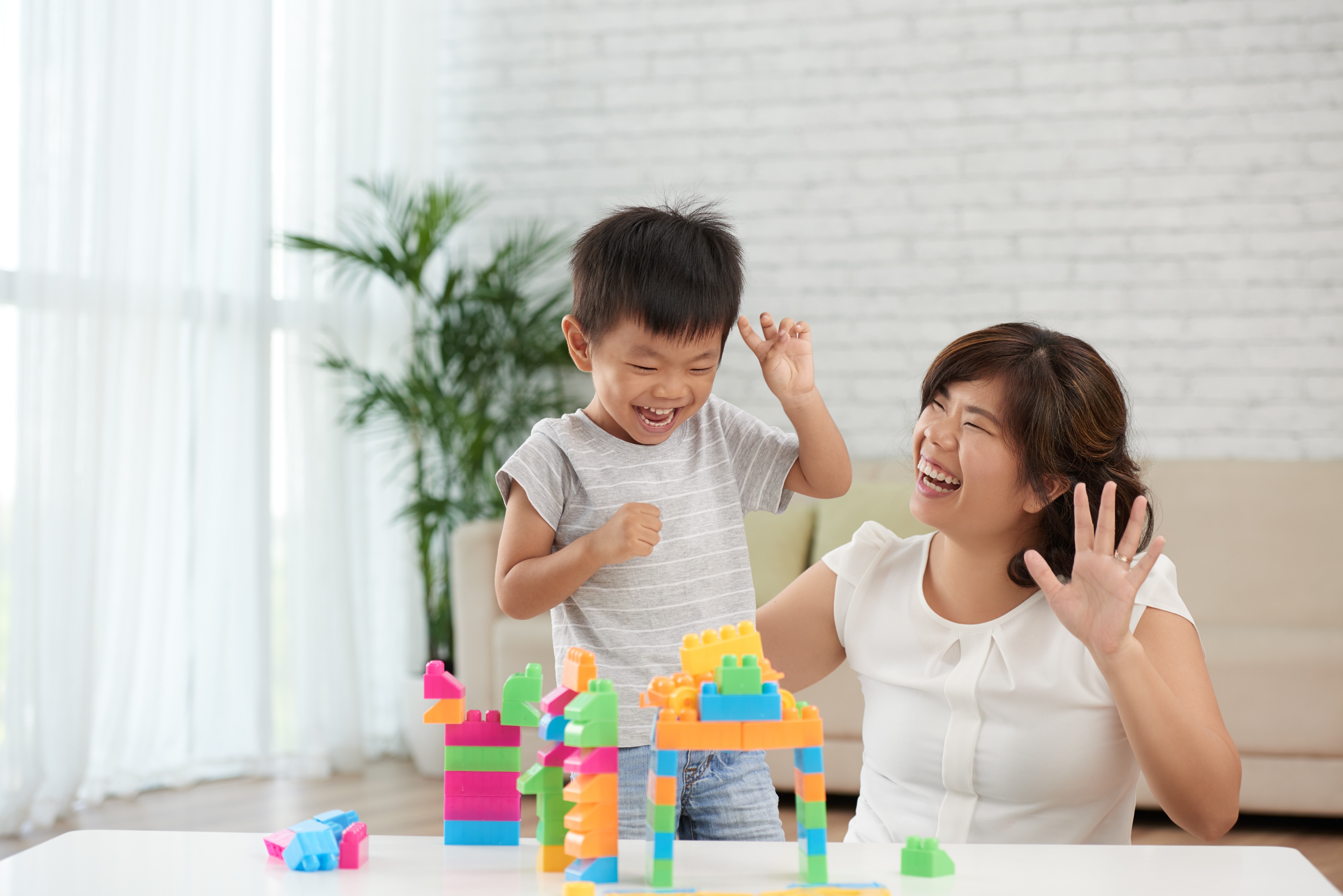 Asian little boy and his mother playing with blocks and having fun