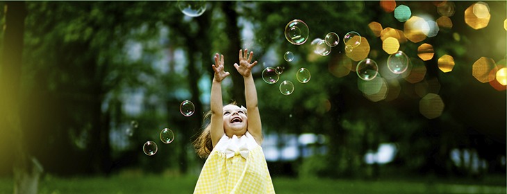 Little girl reaching for bubbles in a meadow. 